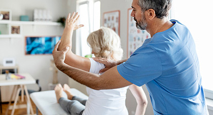 A personal trainer bending a patient arm in a 90 degree angle.